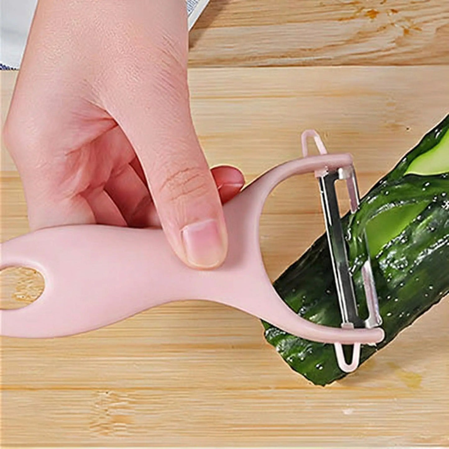 une madame qui utilise un eplucheur rose en plastique avec une lame en acier inoxydable